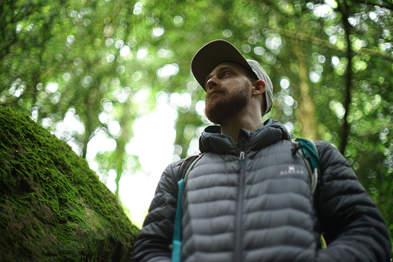 Nick Lewis looking out over moss covered rocks and tree roots in Puzzlewood, Wales.